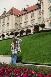 女游客观光假期概念美丽的紫罗兰花城堡花园在背景上毗邻华沙的皇家城堡，从维斯杜拉河一侧。