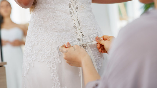 朋友们帮助女人在房间或精品店打结婚纱，准备结婚、合身或穿紧身胸衣花边细节和手。