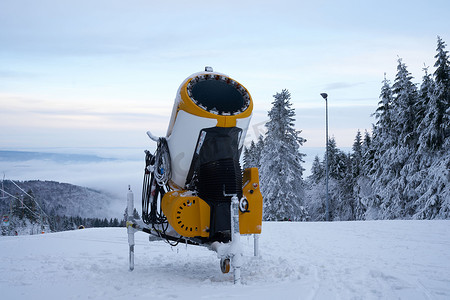 雪扇摄影照片_德国罗恩黑森州 Wasserkuppe 滑雪胜地的黄色人造雪炮，2022 年 12 月新降雪后的雪山上