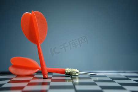 红色的国际象棋摄影照片_放置在棋盘的红色飞镖箭头有深灰背景