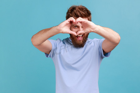 穿蓝色 T 恤的男人透过心形的双手，表现出浪漫的爱情告白