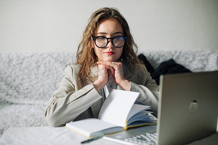 年轻严肃忙碌的职业女商人或戴眼镜的学生使用笔记本电脑观看在线网络研讨会或培训网络课程、看电脑、思考和做研究。