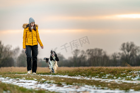 的女孩和她的狗在大自然中的日落散步。