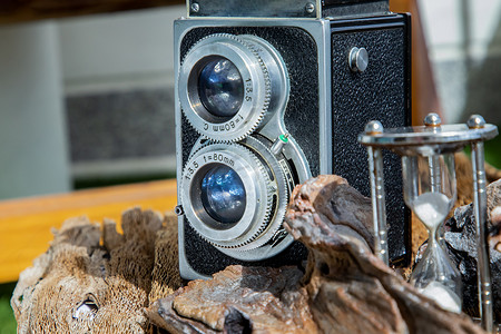 木制背景上带沙漏的老式双镜头相机