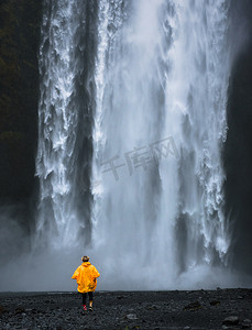 穿着黄色雨衣的游客走到冰岛的斯科加福斯瀑布