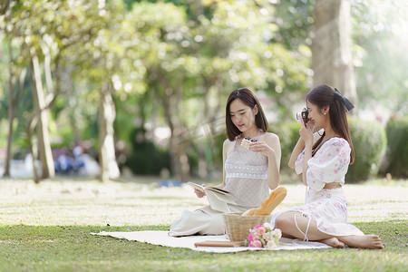 美丽的女人和朋友在阳光明媚的春日在户外公园野餐。
