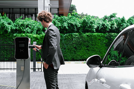 在公共停车场汽车充电站为 EV 汽车充电的进步商人。