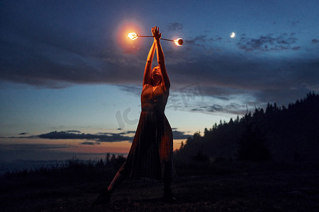 夜间喀尔巴阡山脉中穿着连衣裙的女人的火表演。