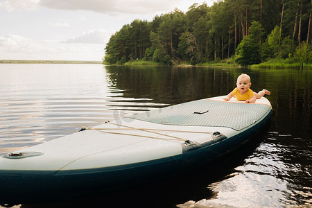 孩子躺在一个大的支撑板上漂浮在水面上。