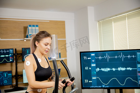 女运动员在踏步机上做体力，并在其上连接电极，结果显示在屏幕上