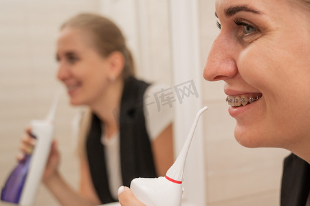 戴牙套摄影照片_一位戴牙套的女士使用冲洗器。