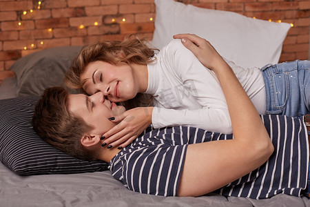 白人年轻漂亮的夫妇躺在床上互相拥抱