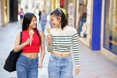 在街上吃冰淇淋的快乐亚洲女性