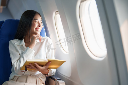 豪华飞机摄影照片_亚洲商务女性乘客坐在商务舱豪华飞机上，同时使用笔记本书工作，同时旅行概念