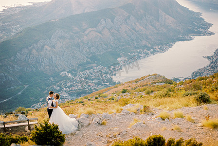 在科托尔湾的背景下，新郎在靠近长凳的洛夫森山上拥抱新娘。