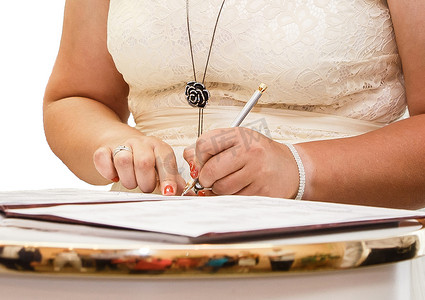 婚礼上女孩的手把签名笔放在杂志上关于结婚登记