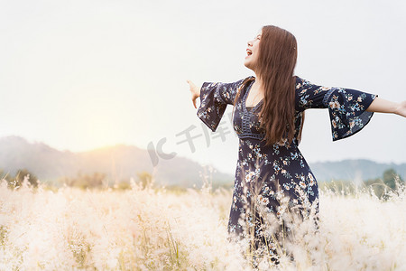 阳光下站在草地上的年轻时髦女性的夏日画像