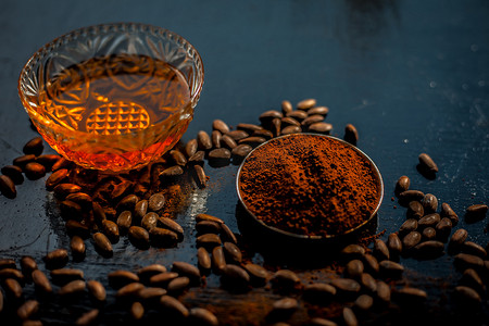 黑色木质表面抗衰老的咖啡面膜，由一些咖啡豆和蜂蜜组成。