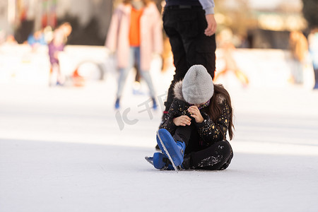 滑冰摔倒摄影照片_人、运动、创伤、疼痛和休闲概念 — 年轻女子在室外溜冰场上摔倒并抱住膝盖