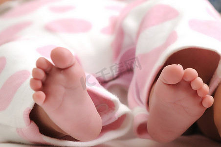 女婴的特写照片，她穿着粉红色的圆点衣服，脚伸出来