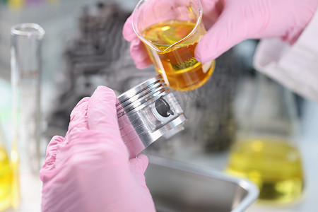 科学家在实验室特写镜头中将机油倒在汽车活塞上