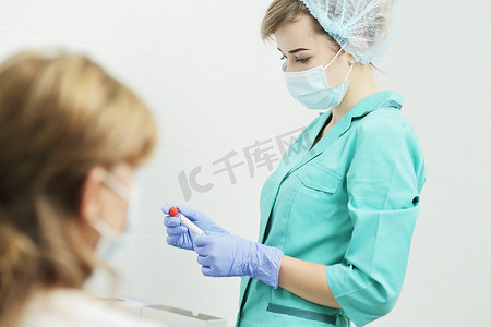一位戴医用面具的女护士拿着试管进行验血