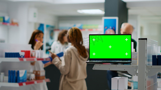 药房货架上带绿屏显示屏的笔记本电脑