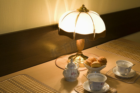 茶杯蛋糕摄影照片_点亮的灯和茶杯配烤饼
