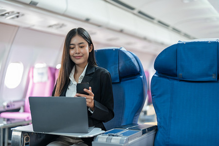 乘飞机旅行摄影照片_商务女性携带智能手机和笔记本电脑乘飞机旅行的交通、旅游和技术概念