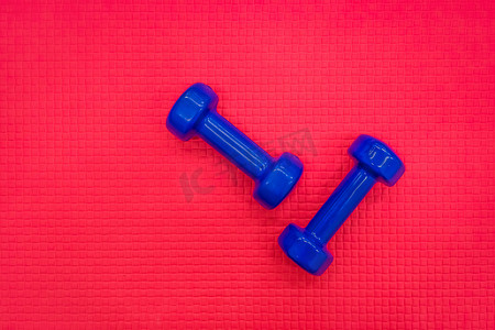 蓝色哑铃摄影照片_在健身房的红色地板背景的蓝色哑铃健身重量设备