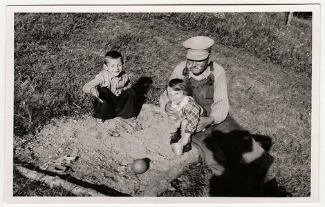 一张老式照片显示祖父和孩子们在沙坑里玩耍。