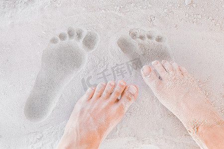 白色沙滩背景特写中男性和女性腿的痕迹
