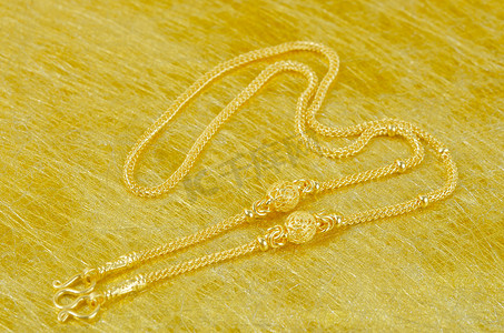 黄金手镯摄影照片_金色背景上的一条金项链。