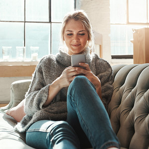 社交媒体上的女人、沙发和智能手机，在互联网上阅读或交流，在休息室放松。