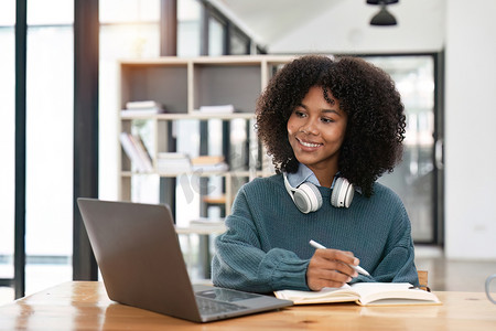 微笑的年轻非洲裔美国少女戴着耳机在笔记本电脑上进行视频通话。