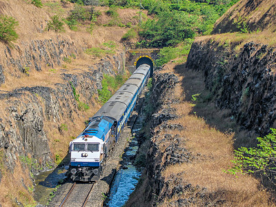 在印度马哈拉施特拉邦康坎地区，一列客运列车驶出隧道进入深坑。