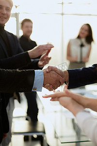 商业伙伴在商业团队的掌声中握手。
