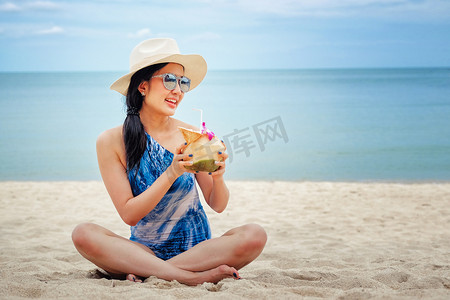新鲜椰子水摄影照片_海滩上有新鲜椰子水的快乐女人