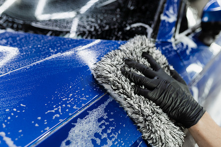 在车库里用泡沫车身用超细纤维手套洗手。