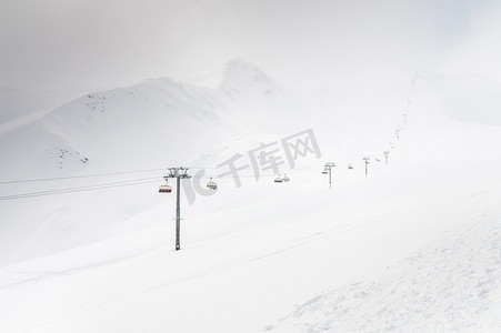 雪天摔跤摄影照片_雪天缆车爬高山，冬天滑雪场