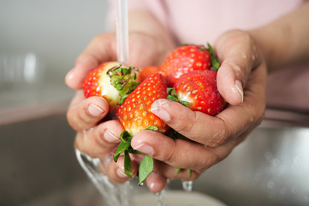 洗草莓草莓摄影照片_新鲜草莓用手洗。