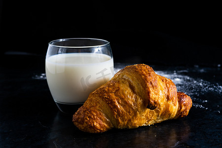白石子主图摄影照片_黑色石桌背景上白色玻璃杯中的新鲜白面包和牛奶。