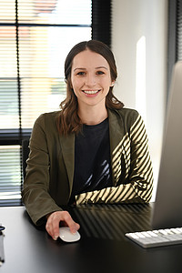 身着优雅西装的白人女经理坐在工作场所，对着镜头微笑的画像