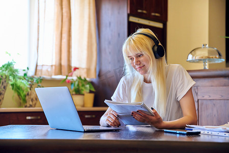 戴耳机的少女学生在家使用笔记本电脑学习。