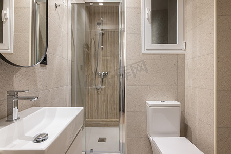 浴室玻璃摄影照片_现代小浴室配有时尚的米色瓷砖、玻璃淋浴间、水槽、卫生间和窗户。
