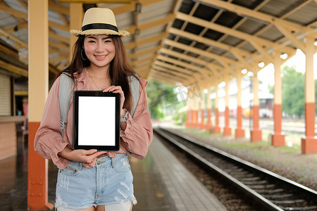 女旅客在火车站展示带有空白屏幕的平板电脑。