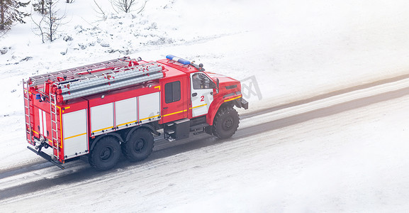 一辆红色消防车或消防车在冬天沿着一条多雪的街道行驶