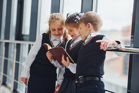 学校的孩子们穿着制服在走廊里一起看书。