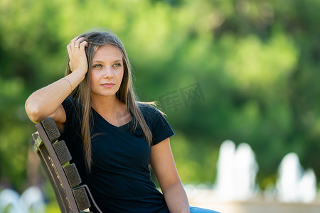 手撑摄影照片_一个女孩坐在长凳上，用手撑着头，特写
