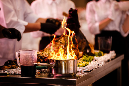 烹饪节目，厨师用火在煎锅中准备食物。